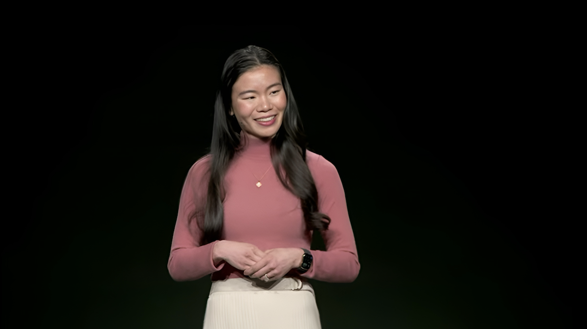 Sharon Zhou is pictured smiling confidently with her hands clasped, reflecting AI’s potential for community-building.